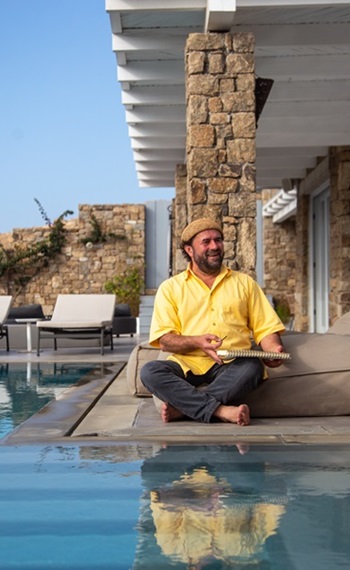 Henry Goldborn im Schneidersitz am Pool sitzend, auf Mykonos